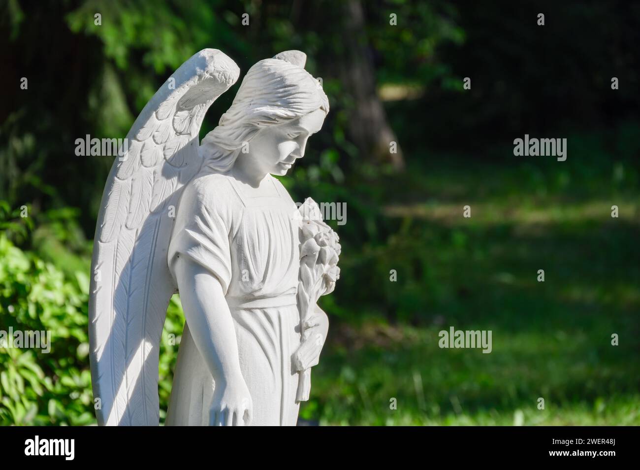 White angel statue at the grave in the cemetery Stock Photo