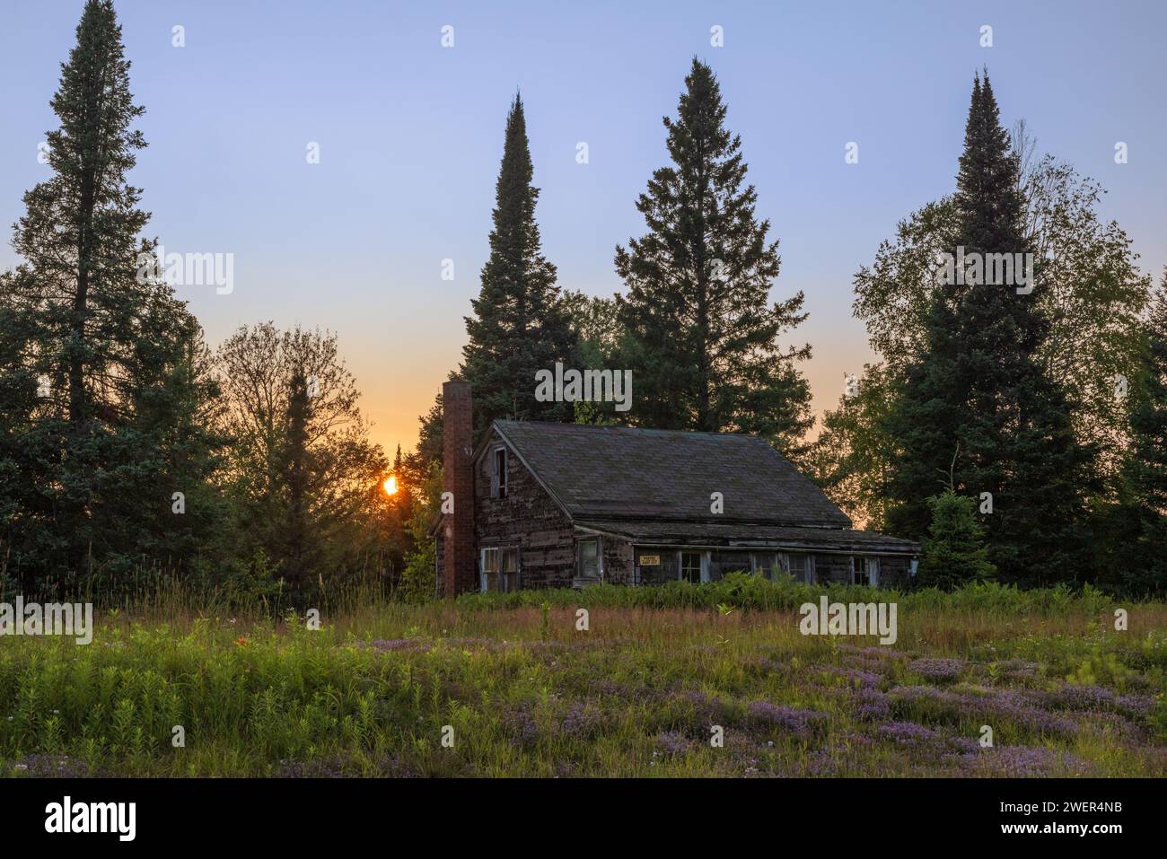 The sun setting behind an old cabin in northern Wisconsin. Stock Photo