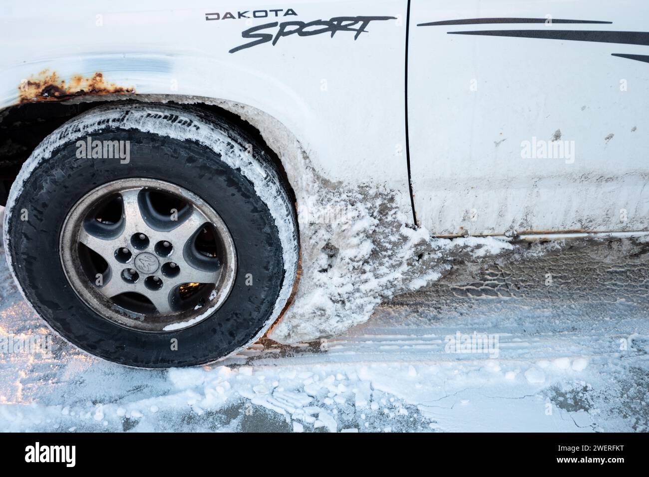 Front wheel of light truck showing snow and ice accumulated behind wheel. Stock Photo