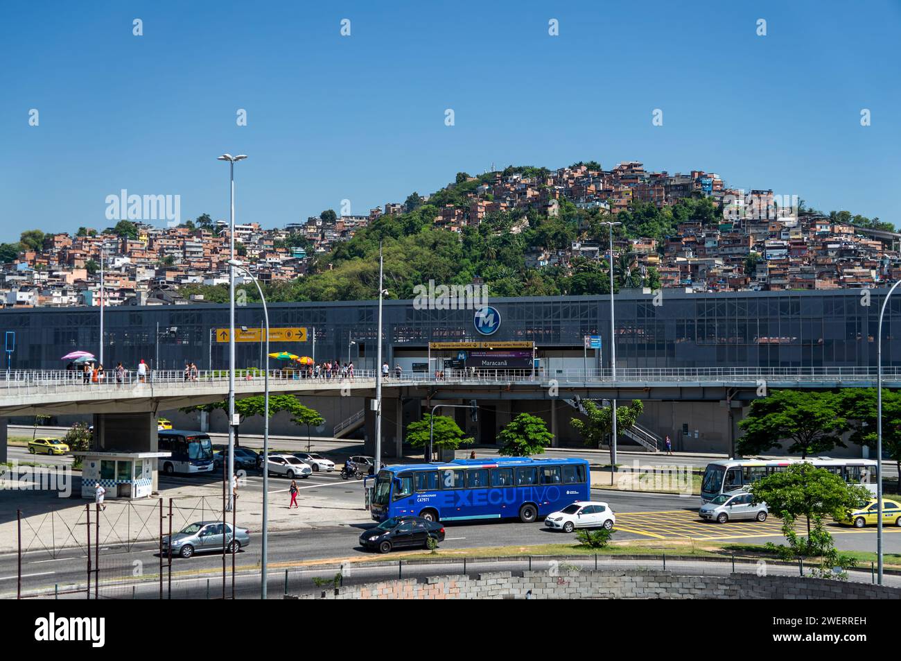 View of Maracana train station building at Rei Pele avenue with Mangueira shanty town community hill at the back under summer morning clear blue sky. Stock Photo