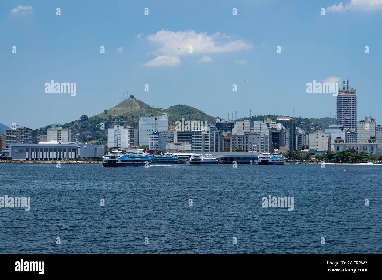 Distant view of Niteroi's Centro district coastline waterfront buildings as saw from Guanabara bay blue waters under summer afternoon clear blue sky. Stock Photo