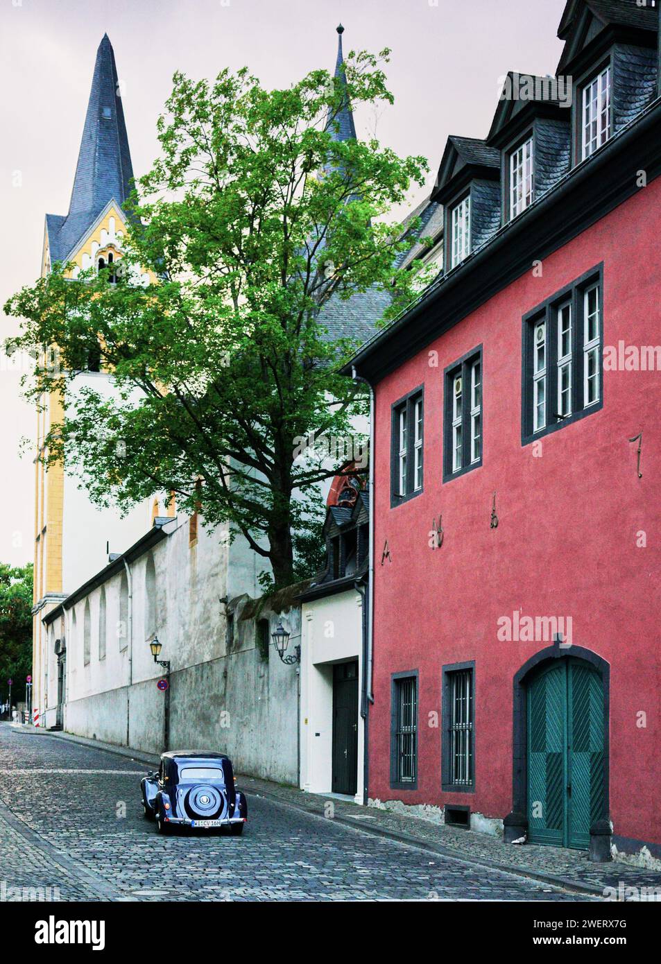Isolated vintage luxury automobile drives down cobblestone street in the historic town of Koblenz, Germany.  No people.  1940's recreation look. Stock Photo