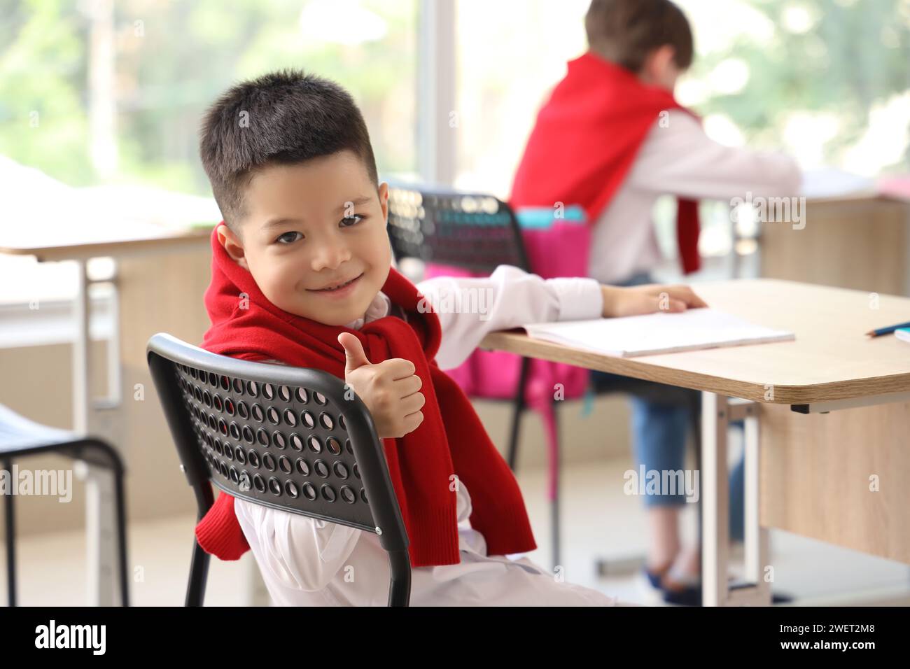 Little schoolboy showing thumb-up in classroom Stock Photo - Alamy