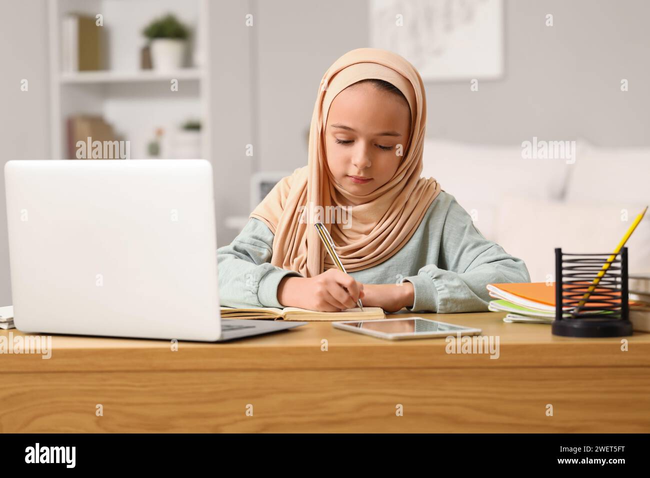 Little Muslim girl in hijab doing homework at home Stock Photo - Alamy