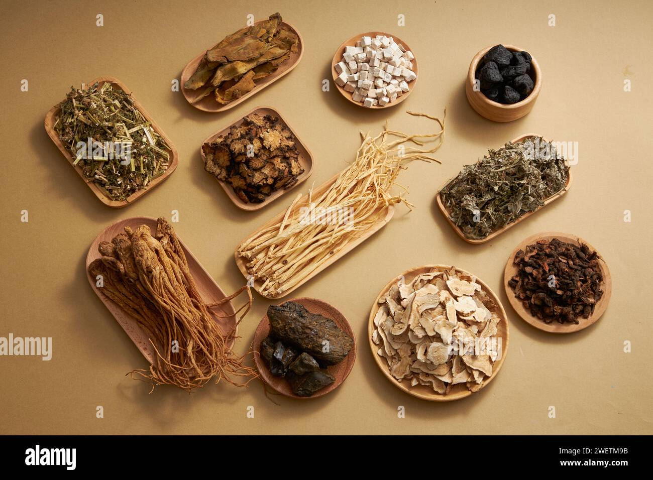 Traditional Chinese medicine with herbs placed in wooden plates on light brown background. Top view, scene for medicine advertising Stock Photo