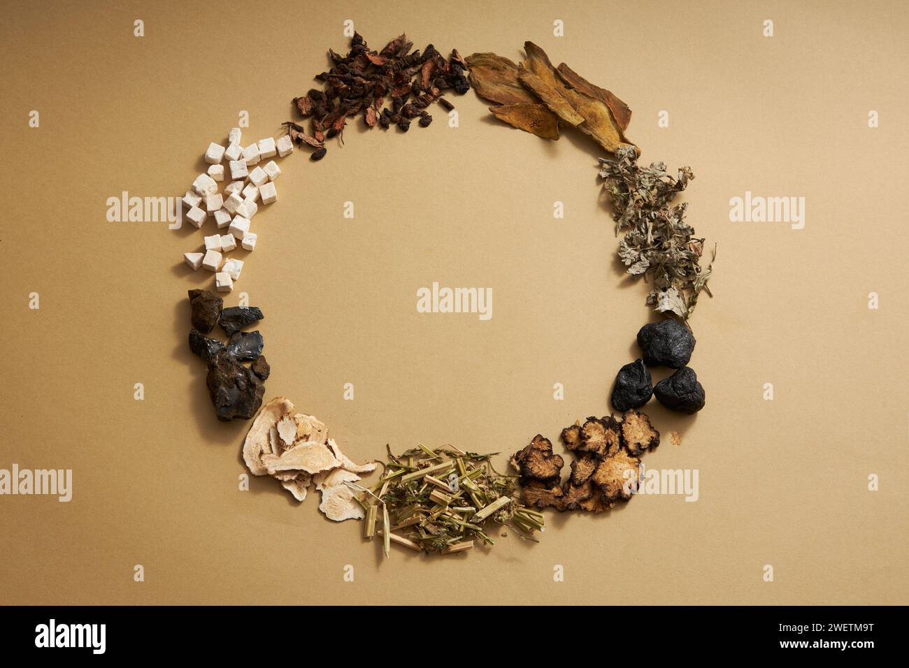 Top view of traditional Chinese medicines arranged in a circle on light brown background. Herbs to help supplement and enhance health. Empty space for Stock Photo