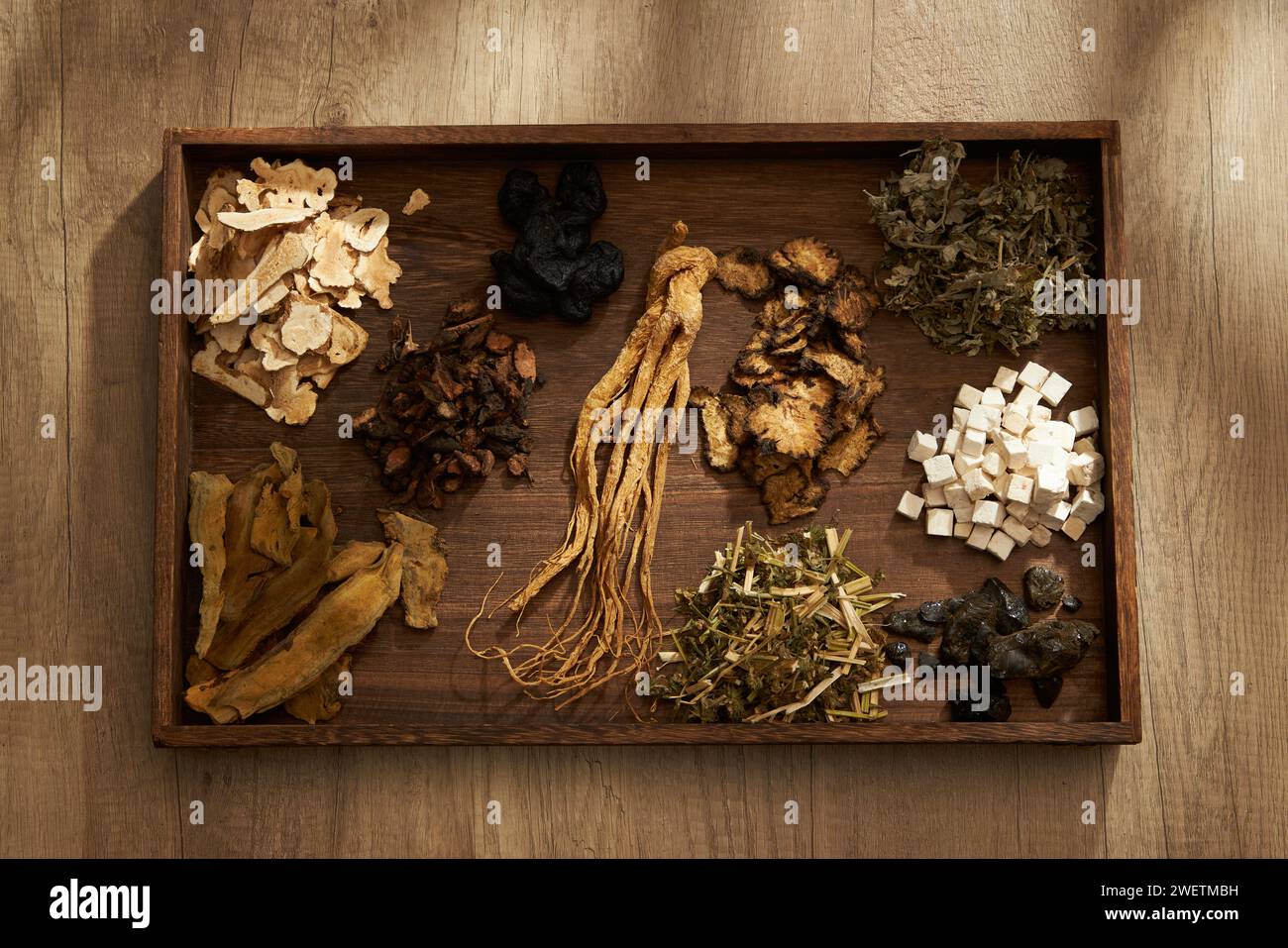 Top view of traditional Chinese herbs placed on a dark wooden tray, on wooden table background. Scene for medicine advertising, photography traditiona Stock Photo