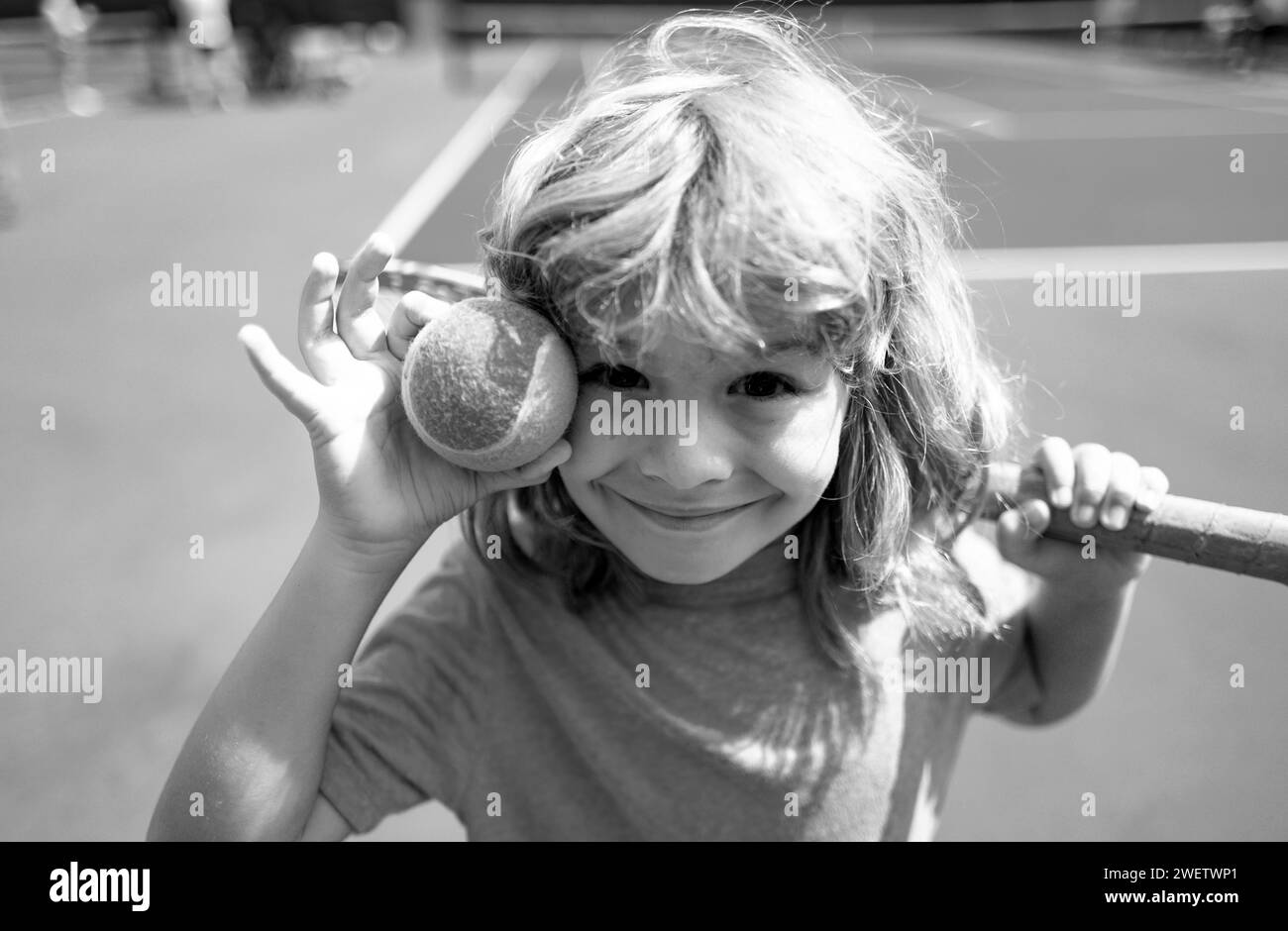 Kid tennis player on tennis court with racket and balls. Stock Photo