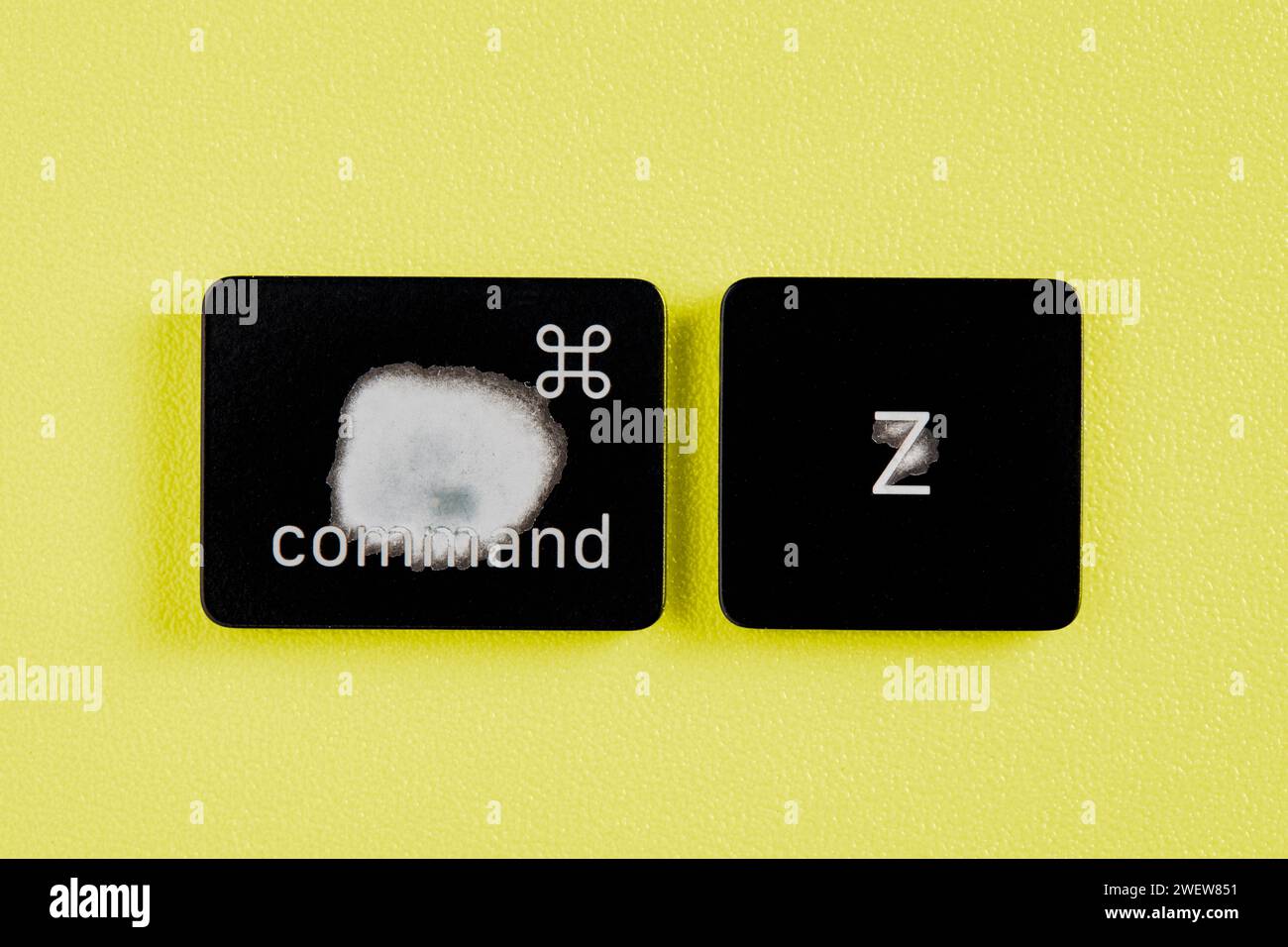 The command key and Z key are worn out due to frequent use and are removed from a keyboard with yellow background Stock Photo
