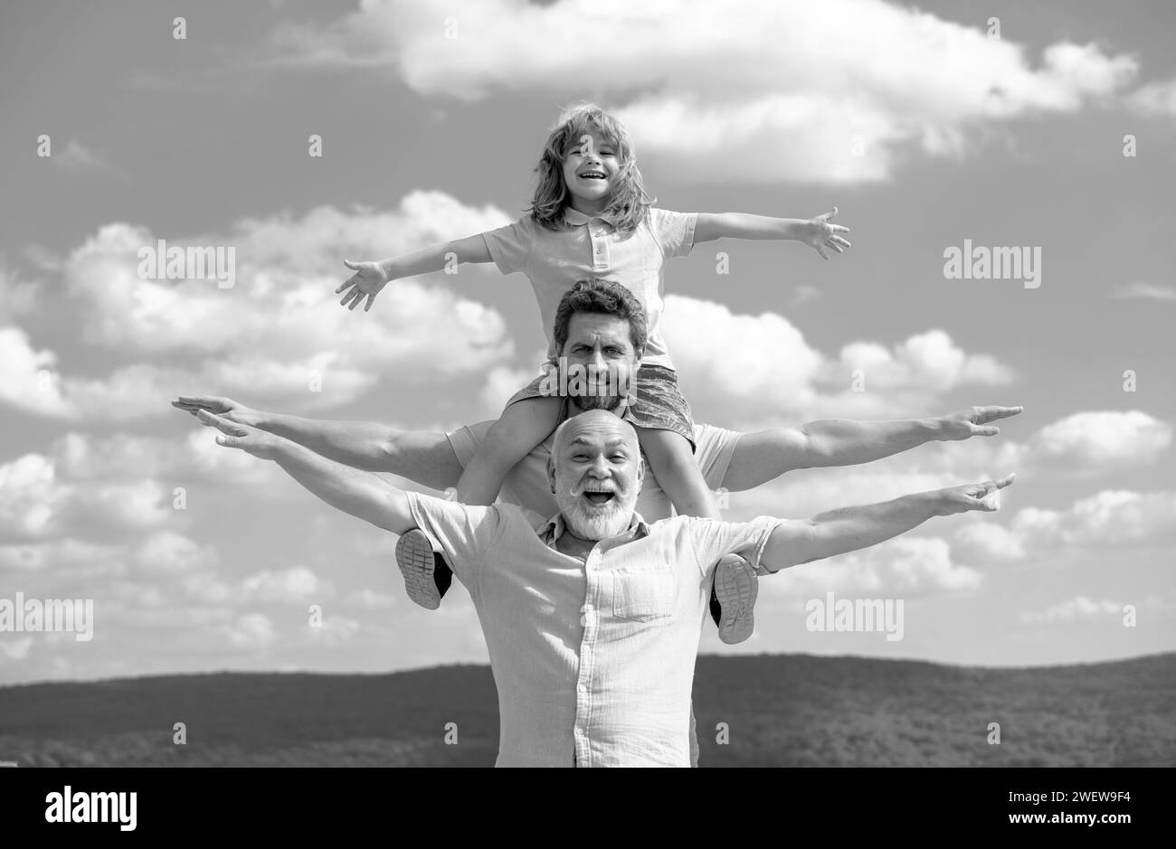 Grandfather with son and grandson having fun, raising hands or open arms flying on sky. Start, creativity startup concept. Stock Photo