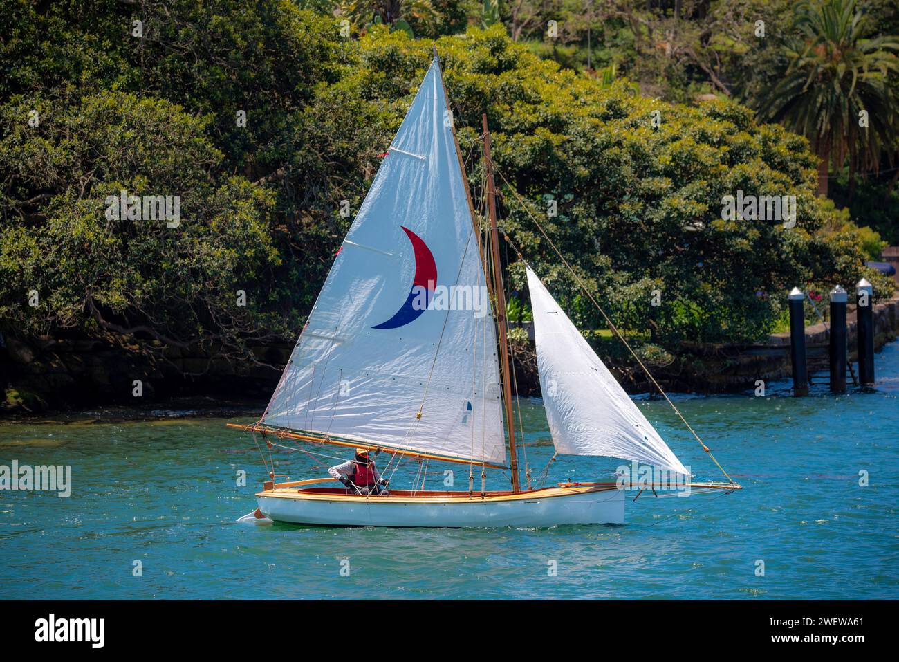 An open wooden sailing boat with a gaff rigged mainsail and jib sail set, sailing on Sydney Harbour in Australia on a sunny day Stock Photo