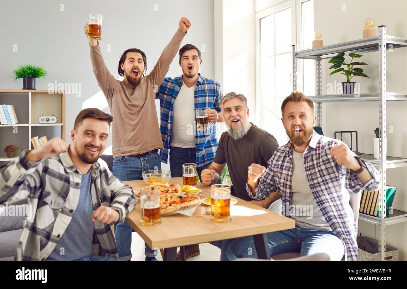 Group of male friends enjoying weekend, having party, watching football, and cheering Stock Photo