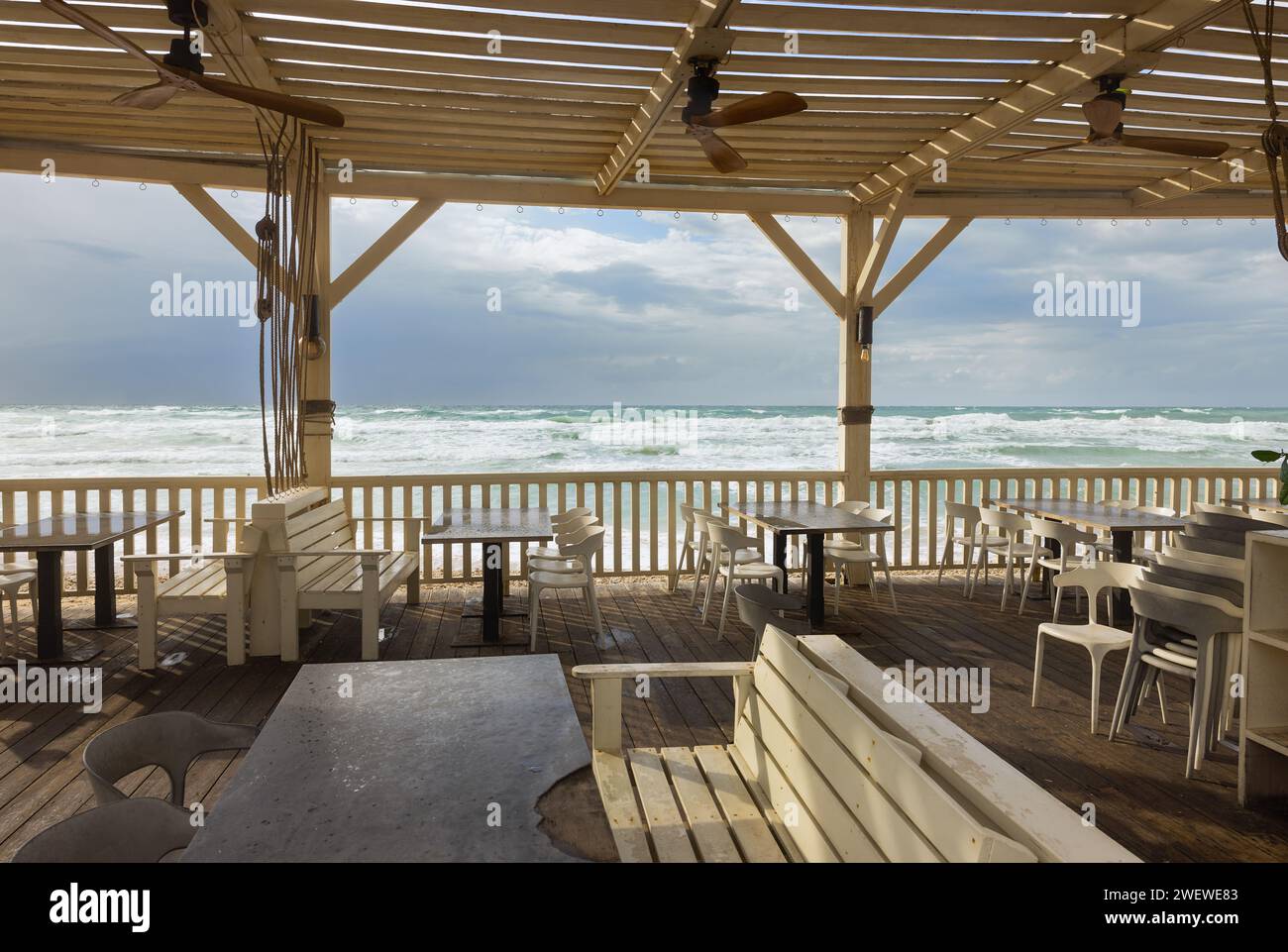 wooden tables with benches and a canopy on the seashore in Haifa Stock Photo