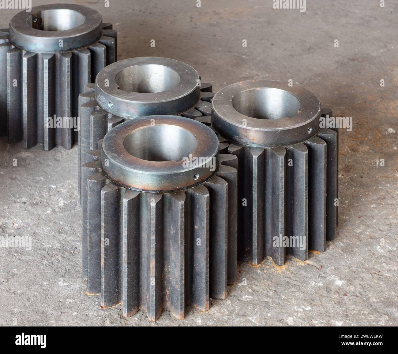 Large, heavy duty cogwheels for industrial applications on a concrete factory floor. Stock Photo