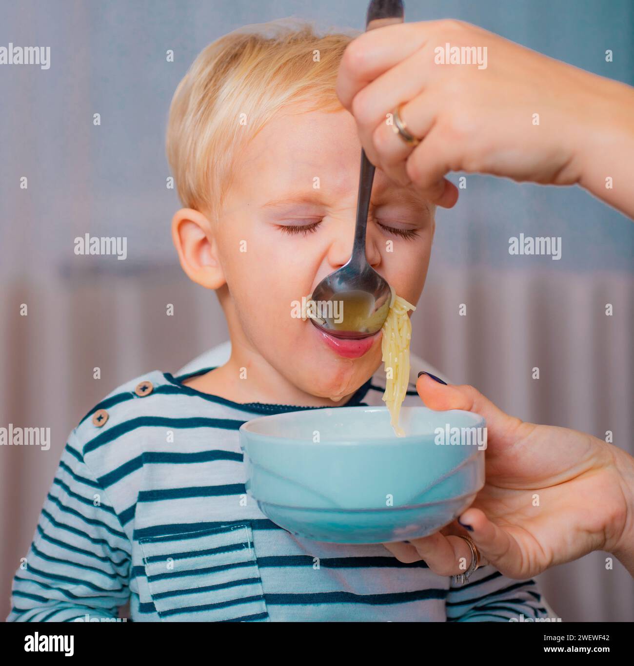 Mom feeding son. Boy cute baby eating breakfast. Child eat soup. Kid ...