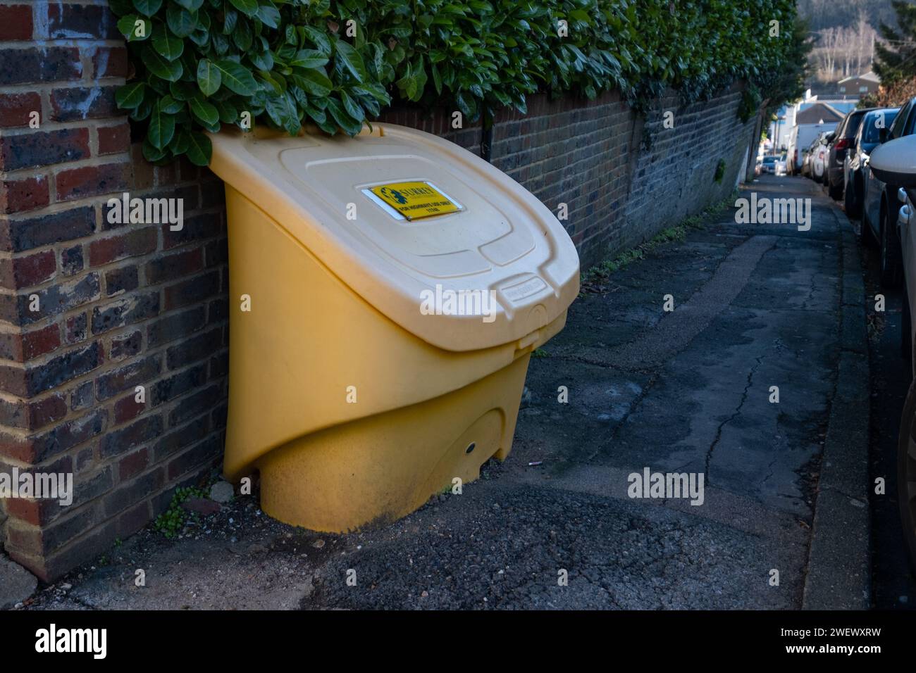 A Surrey council yellow grit container at the top of a steep hill on Grovehill road Stock Photo