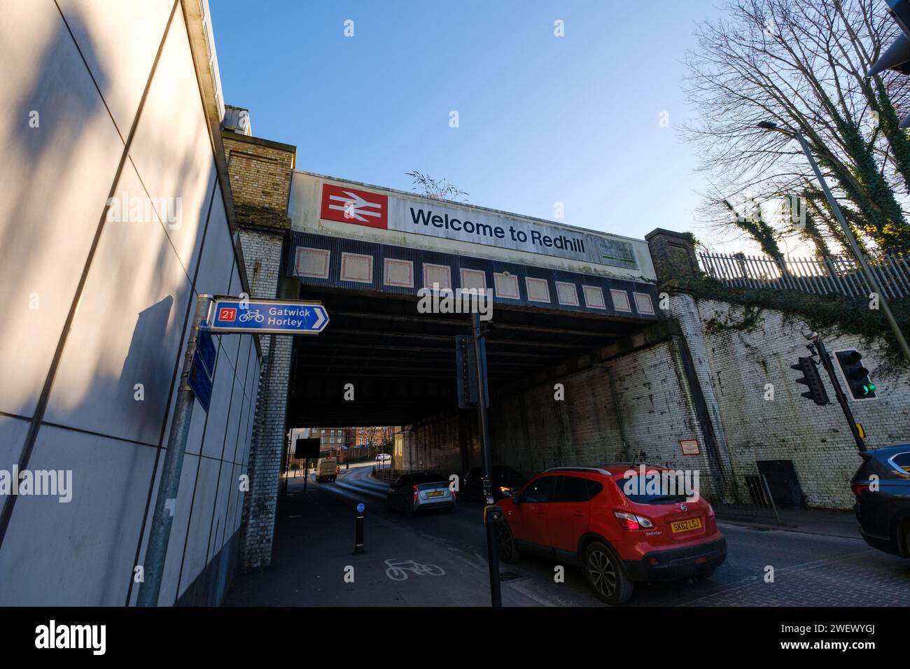 The railway bridge next to the train station in Redhill Surrey with Welcome to Redhill sign and British rail logo showing A25 road and cycle routes. Stock Photo