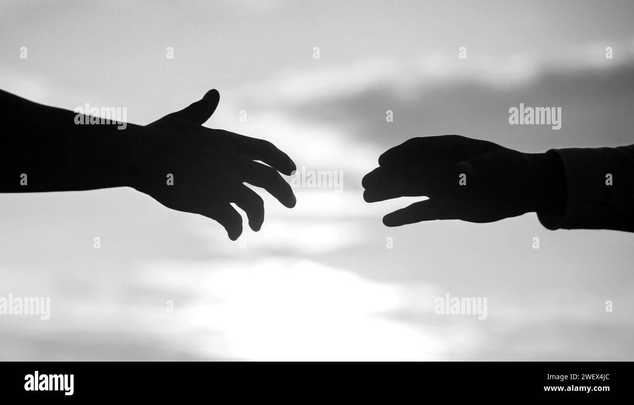 Outstretched hands, salvation, help silhouette, concept of help. Giving a helping hand. Rescue, helping gesture or hands. Stock Photo