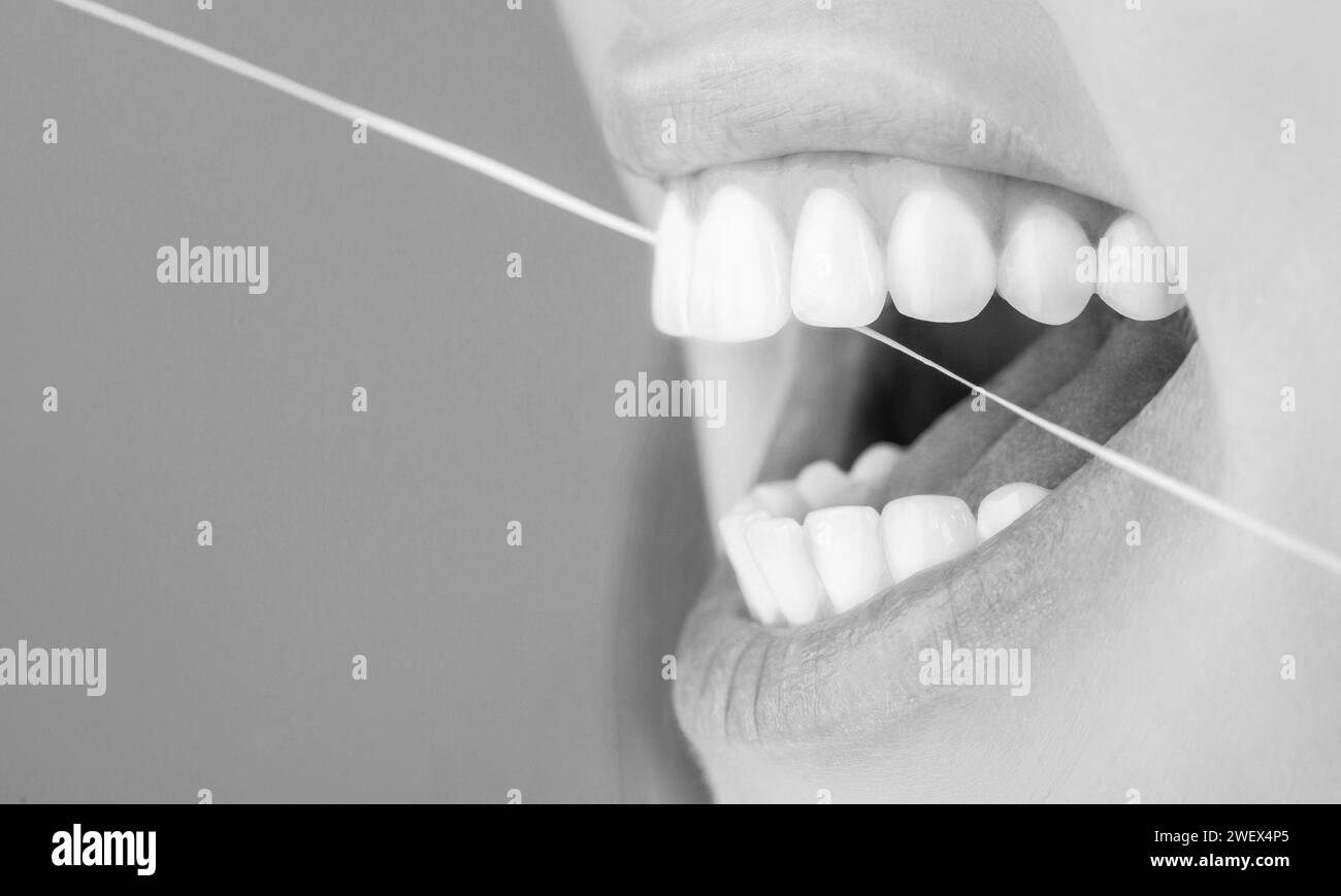 Dental floss. Taking care of teeth. Healthy teeth concept. Teeth Flossing. Smiling women use dental floss white healthy teeth. Black and white Stock Photo