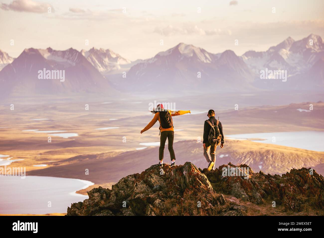 Young couple of hikers with backpacks is walking at mountain top with great view Stock Photo