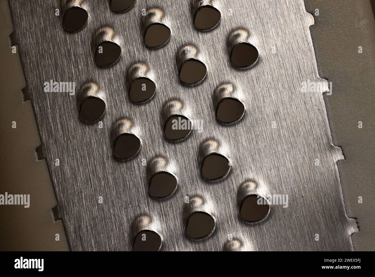 lose up or macro photo of the sharp metal on a Cheese Grater, that is used to shred Cheese. Stock Photo