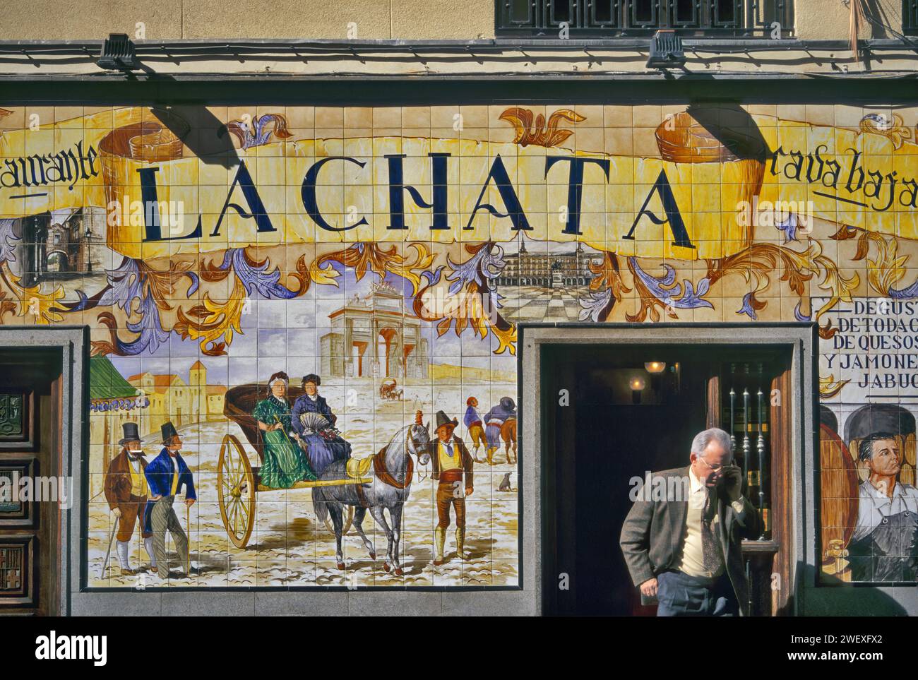 Azulejo tiled facade, man talking on cell phone, La Chata restaurant, Cava Baja, Madrid, Spain Stock Photo