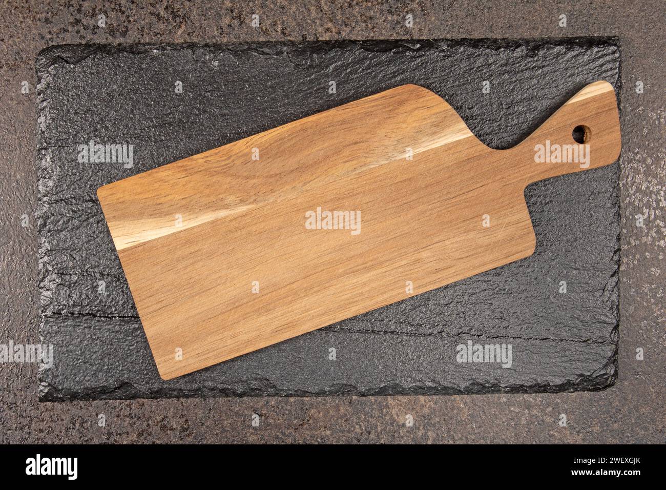 A top-down view of a collection of black stone and wooden cutting boards, providing a rustic and modern mix, with ample space for adding text. Ideal f Stock Photo