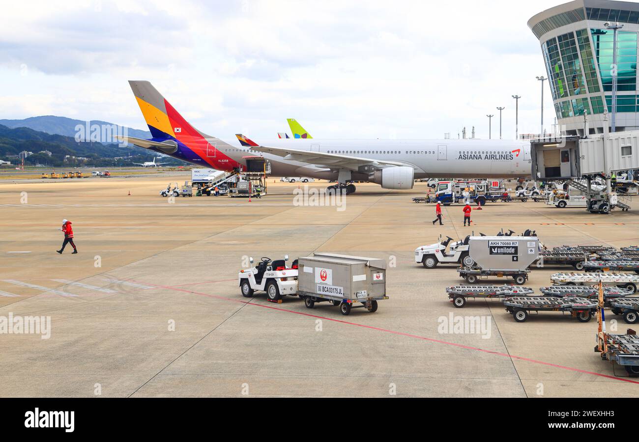 Airport baggage tug (baggage dolly carriage) on duty for ground handling services at FUKUOKA iNTERNATIONAL AIRPORT. Stock Photo