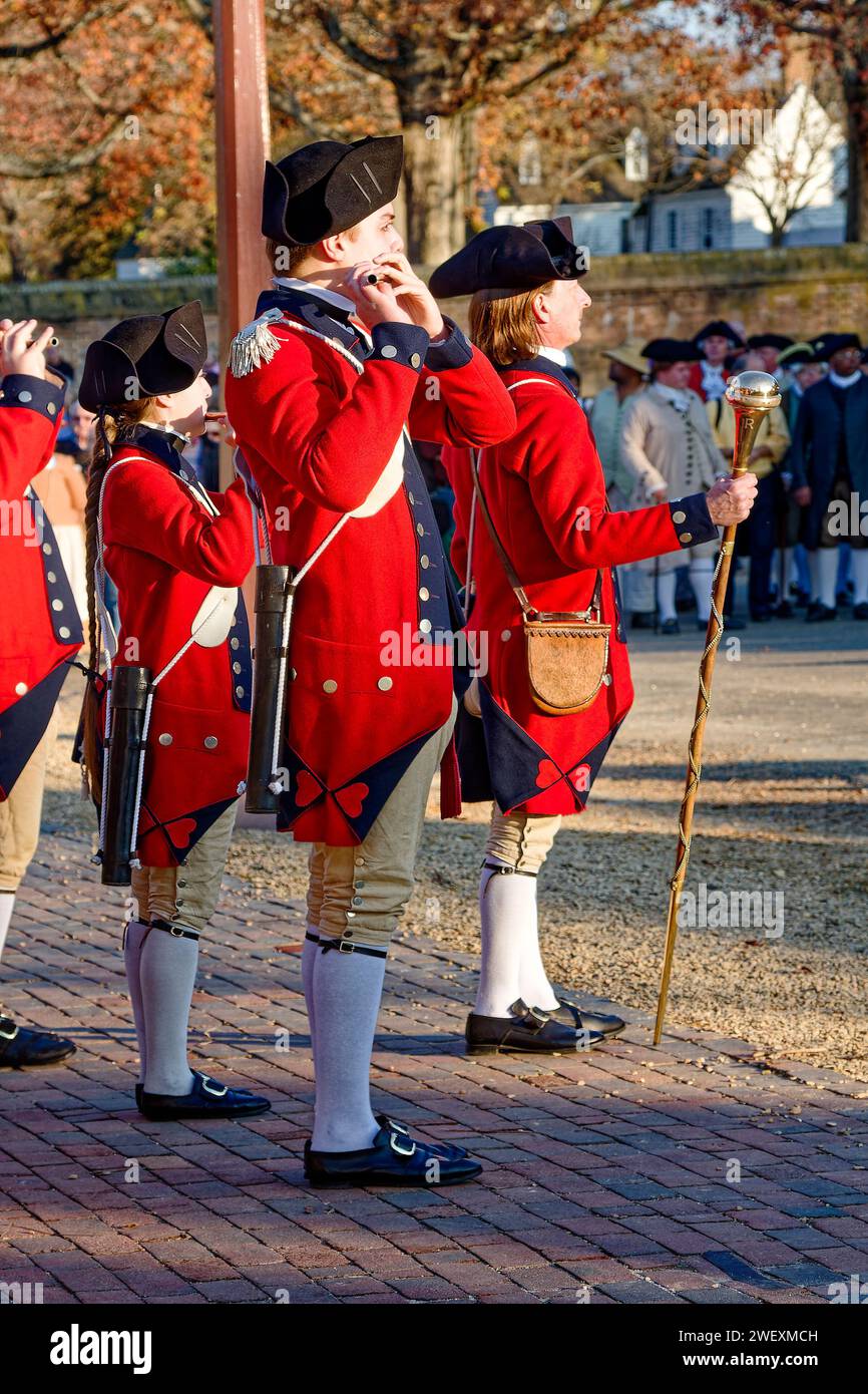 Fifes and Drums Regiment, standing outdoors, fifes playing, Director holding long baton, red