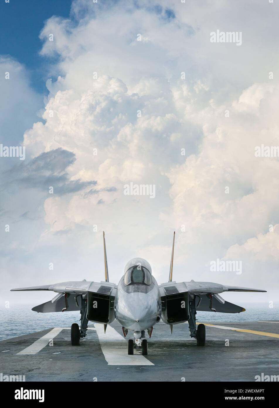 An F-14 jet fighter on an aircraft carrier deck beneath dramatic clouds viewed from front Stock Photo