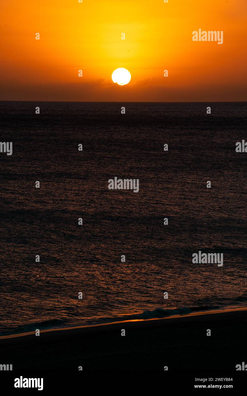 Vibrant sunset over the ocean with a breathtaking orange sky and scattered clouds Stock Photo