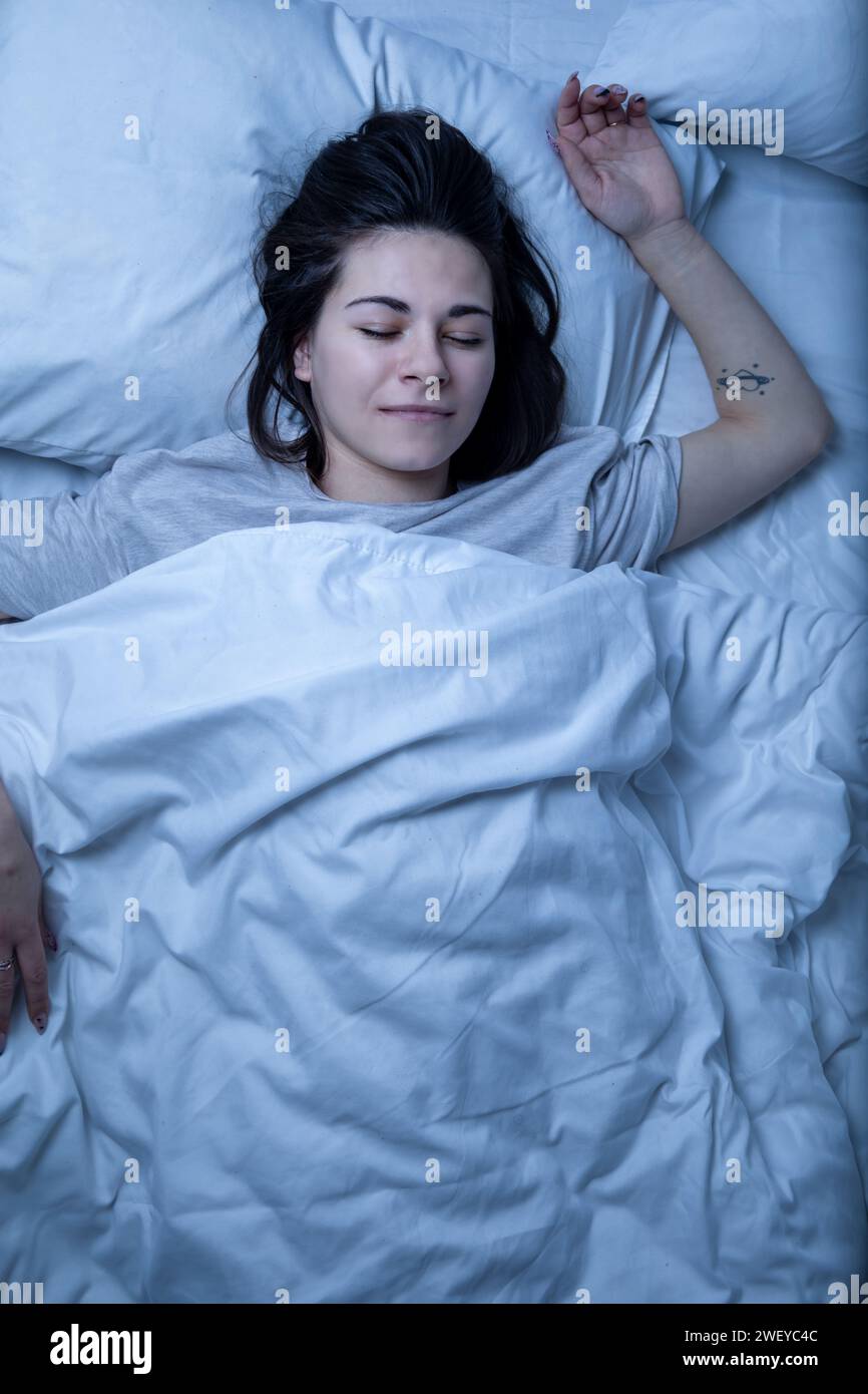 A beautiful girl is sleeping in a bed with a white sheet Stock Photo ...