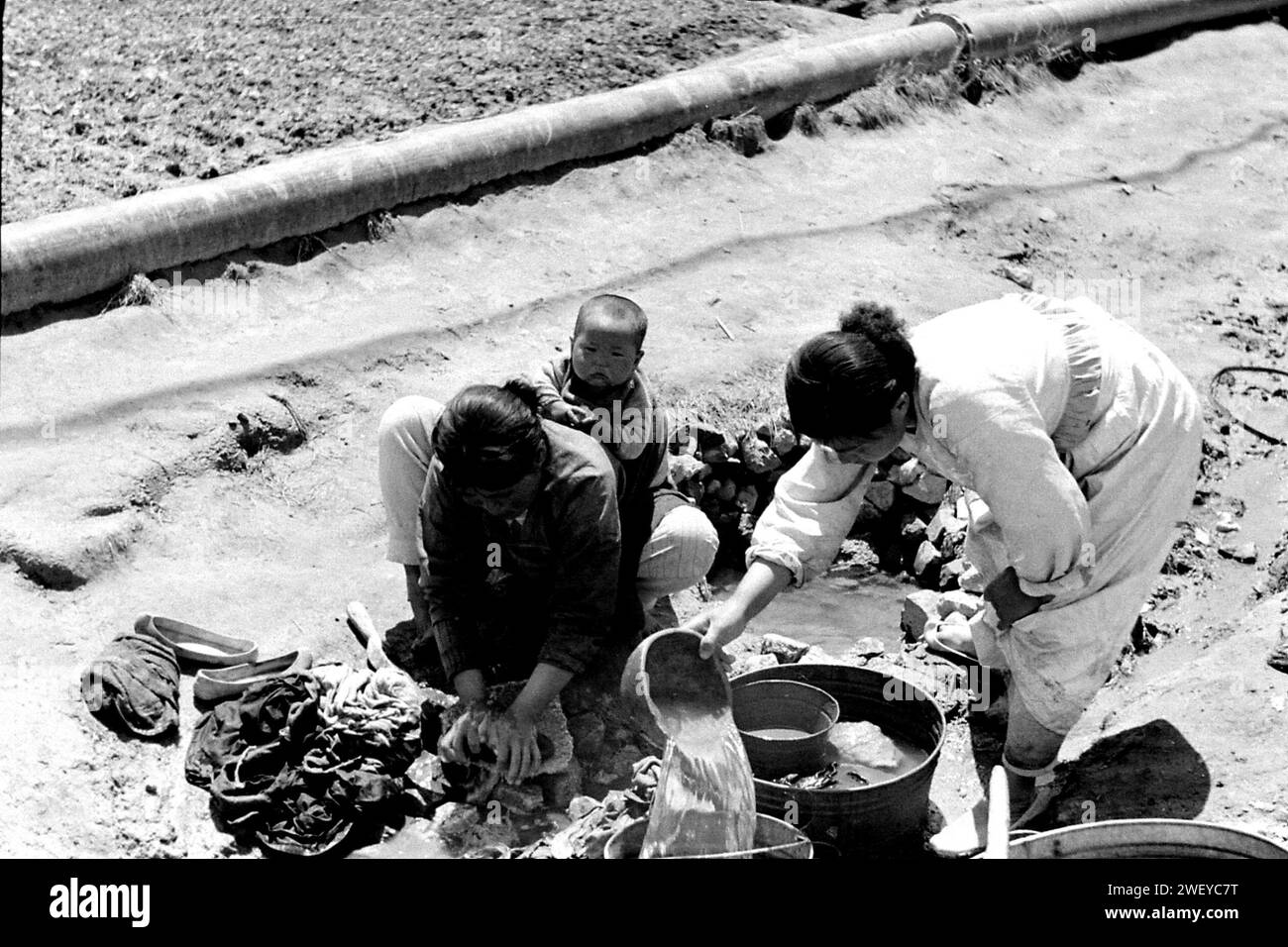 Washing Clothes At A Well Beside The Petrol Oil And Lubricant Pipeline Inchon South Korea 1953 Stock Photo