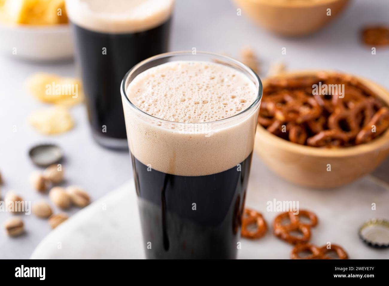 Dark stout beer in tall glasses with nuts, pretzels and chips Stock Photo