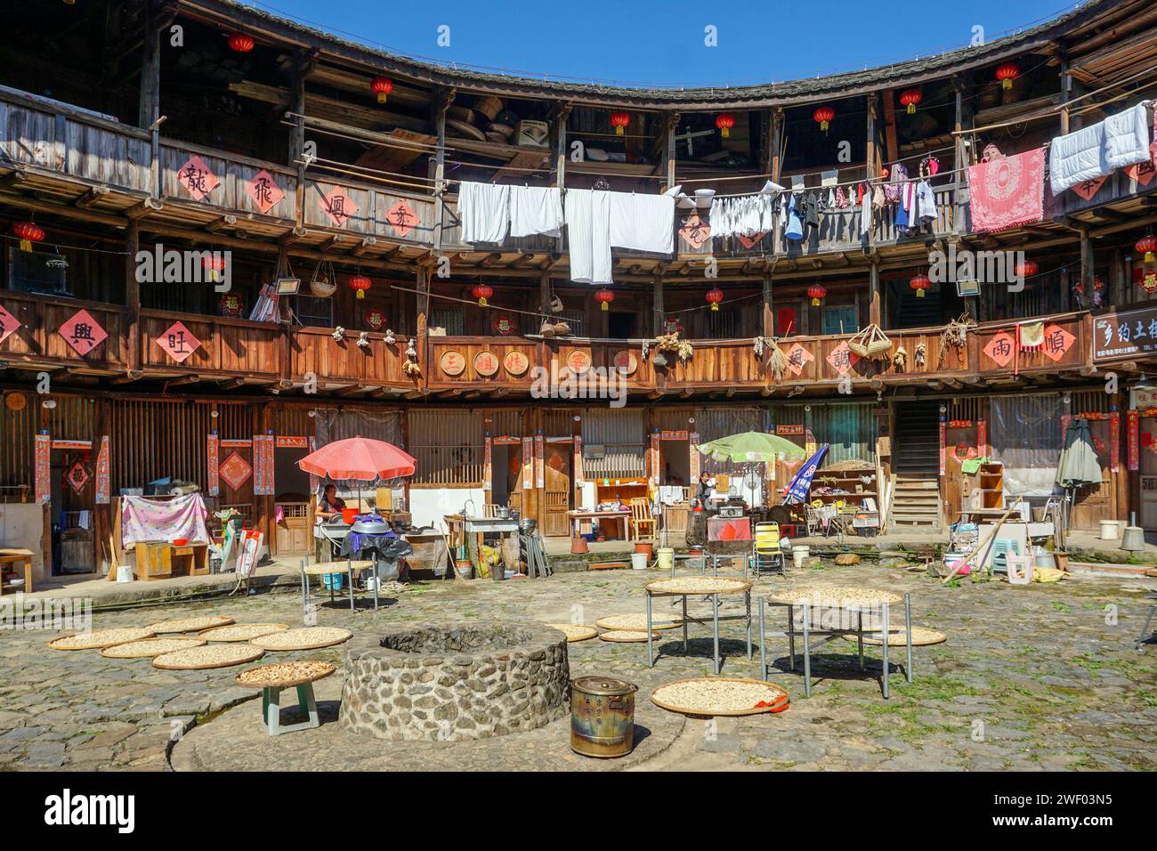 Drying the harvest and grain in the courtyard of a Hakka Tulou (building made of rammed earth and timber) in Nanjing County, Fujian, China Stock Photo