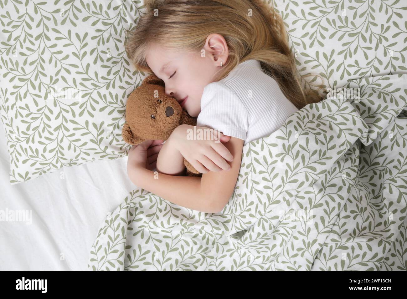 Sweet little girl sleeping in the bed and hugging her teddy bear Stock ...