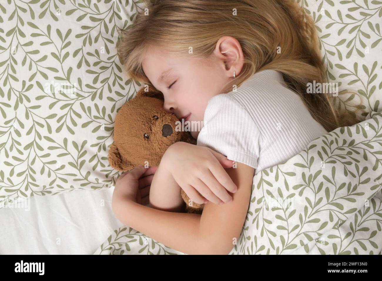 Sweet little girl sleeping in the bed and hugging her teddy bear Stock ...