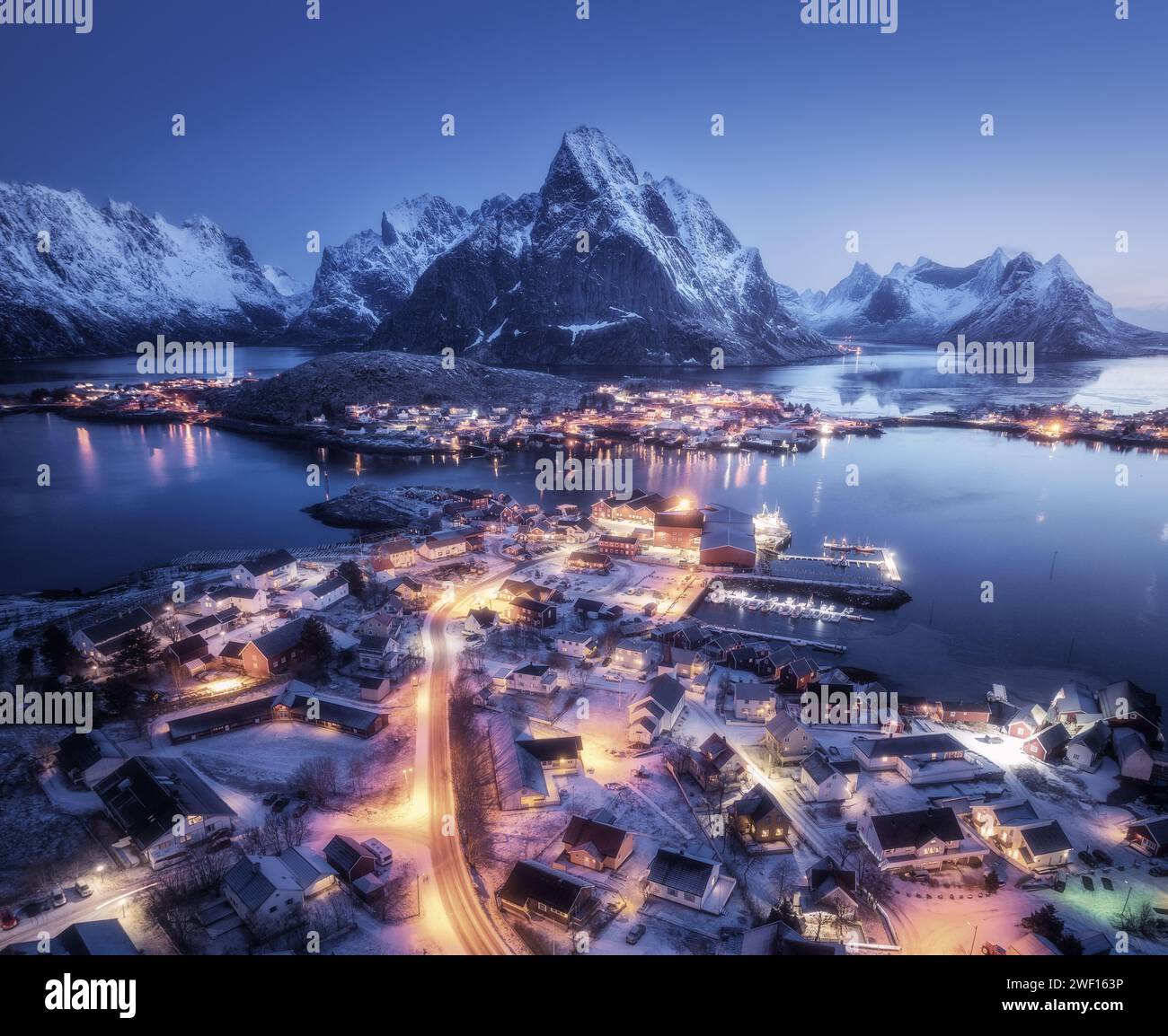 Aerial view of snowy village, city lights, sea, mountain at night Stock ...