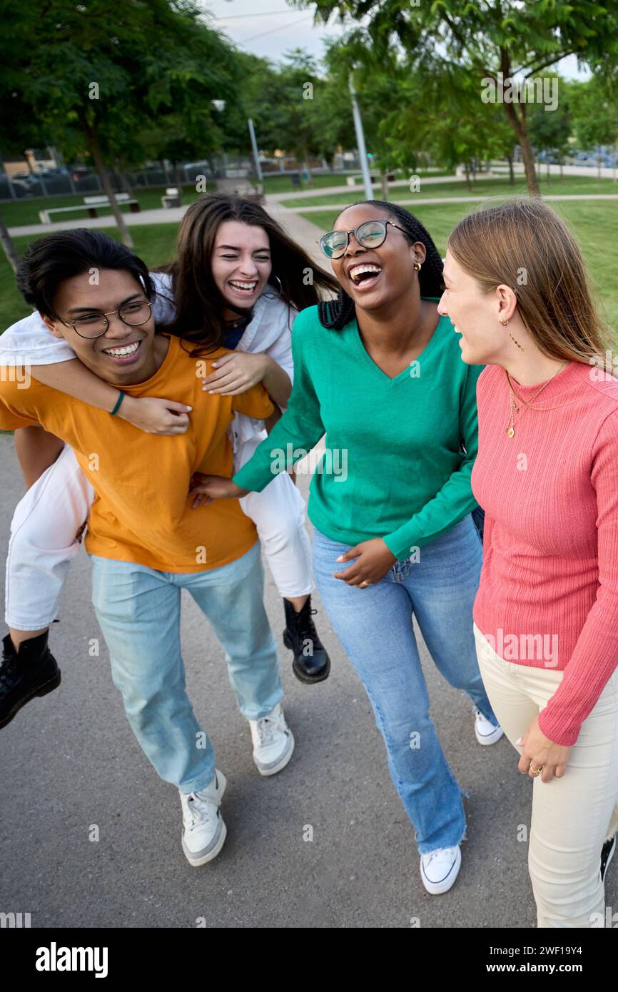 A large multiracial group of teenagers laughing and having fun piggybacking together Stock Photo