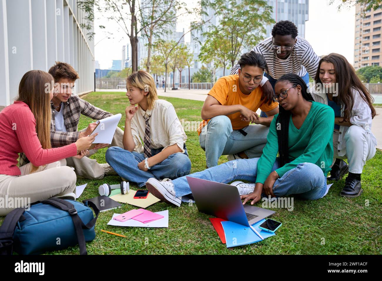 Group of young international university students sitting on the grass ...