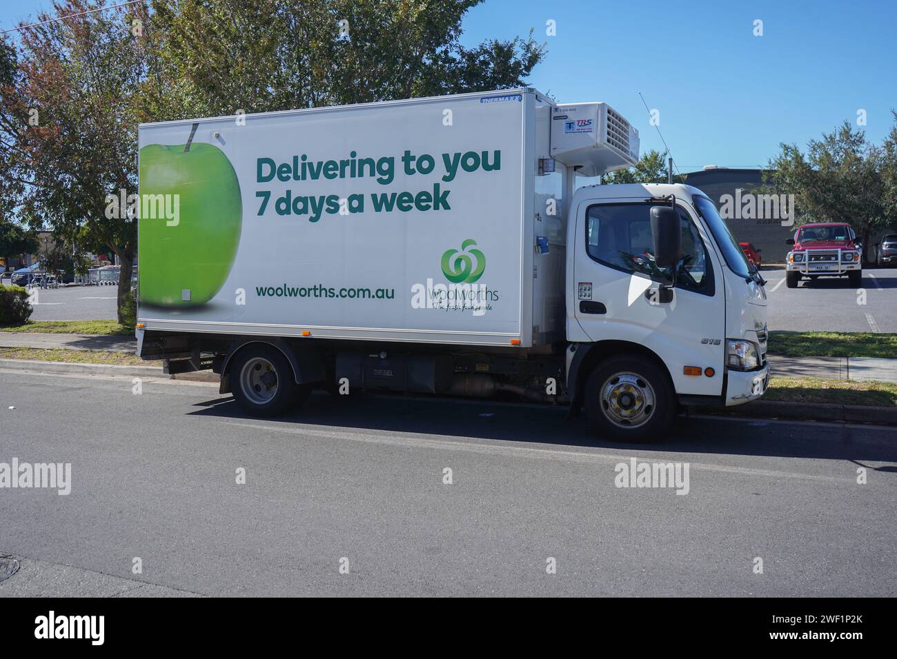 A Woolworths grocery delivery truck parked in a suburban street in