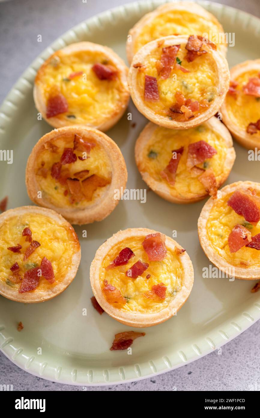 Mini quiches with ham and cheese topped with crispy bacon, ideas for Easter brunch or breakfast Stock Photo