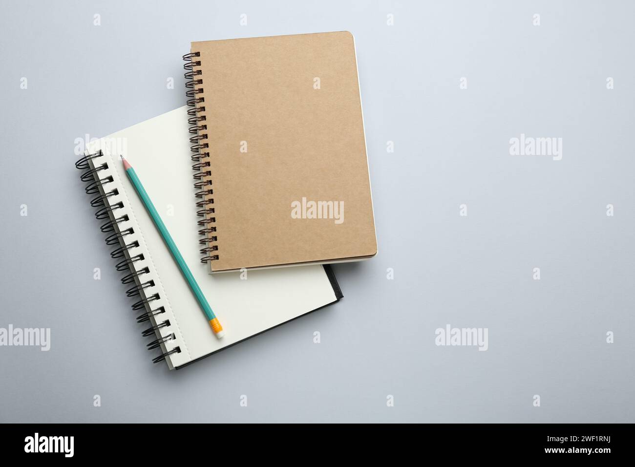 Notebooks and pencil on light grey background, top view. Space for text Stock Photo