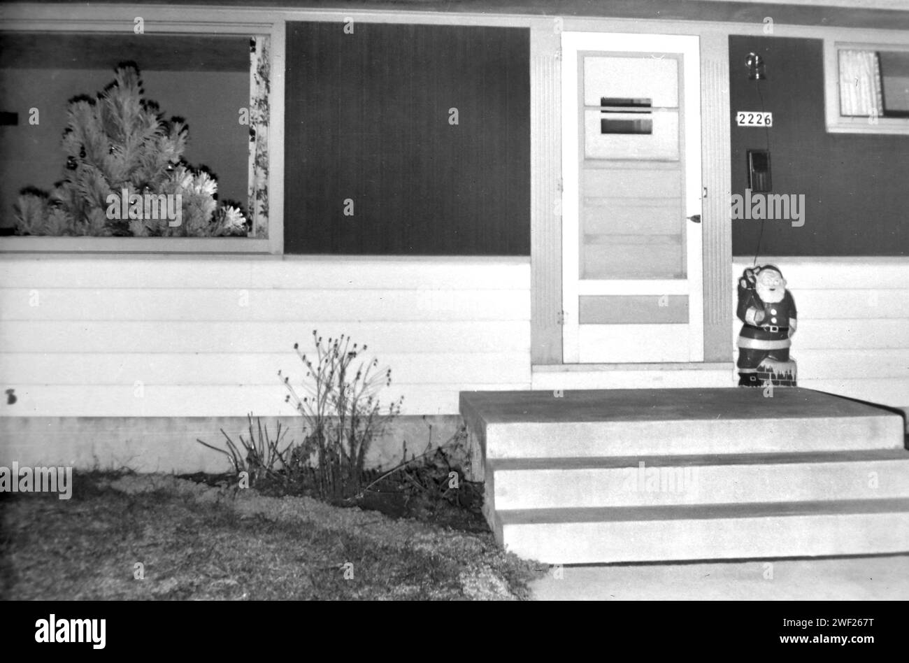 Mid century ranch seen from the front with Christmas tree and Santa Claus, ca. 1960. Stock Photo