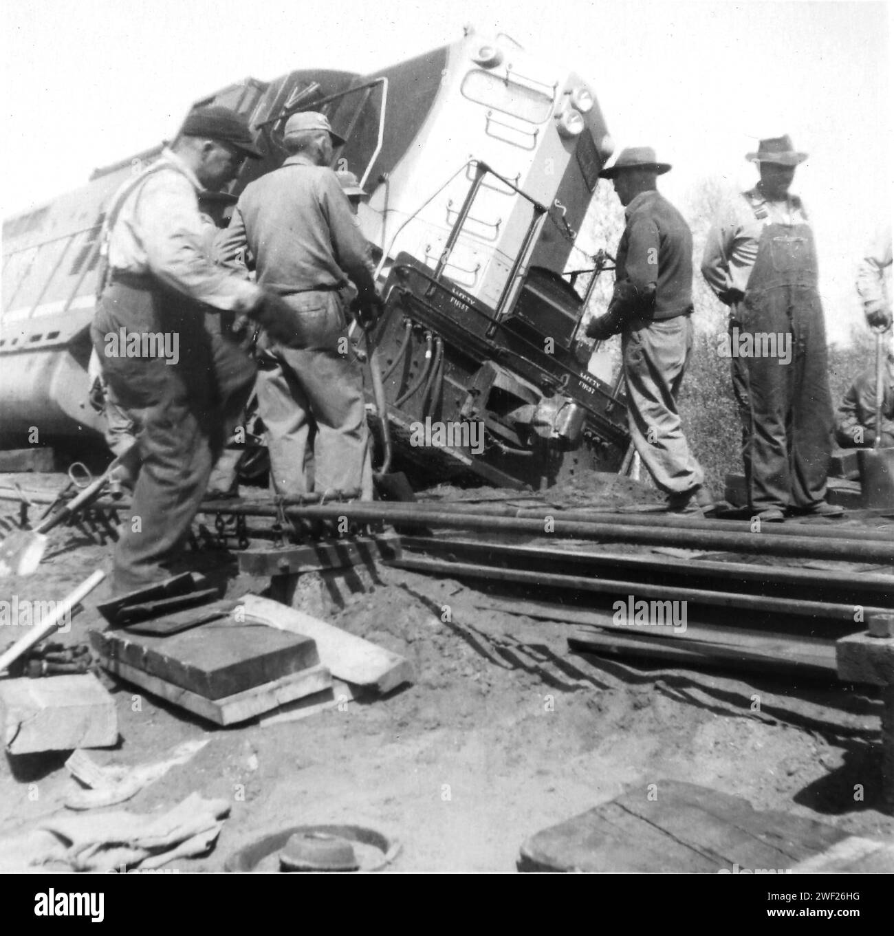 Repair workers gather around a derailed railroad train, ca. 1948. Stock Photo