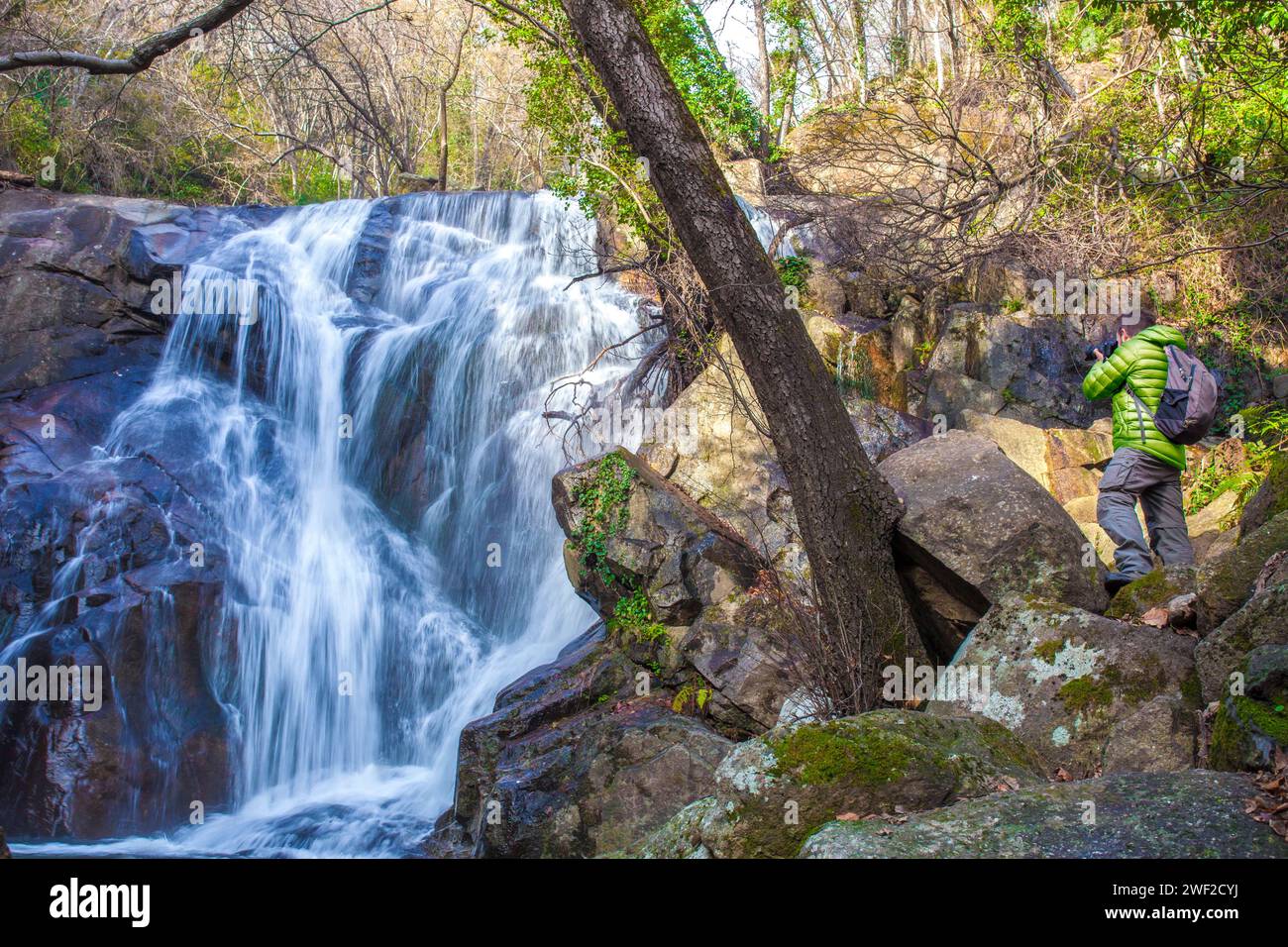 Trekker man taking pictures to Nogaleas waterfall on winter. Navaconcejo, Caceres, Extremadura, Spain Stock Photo