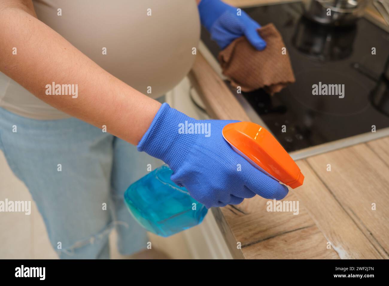 The pregnant woman is cleaning the kitchen, holding her belly while ...