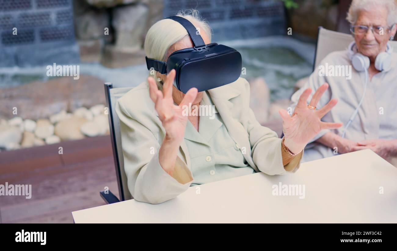 Senior woman gesturing while using virtual reality goggle in geriatric Stock Photo