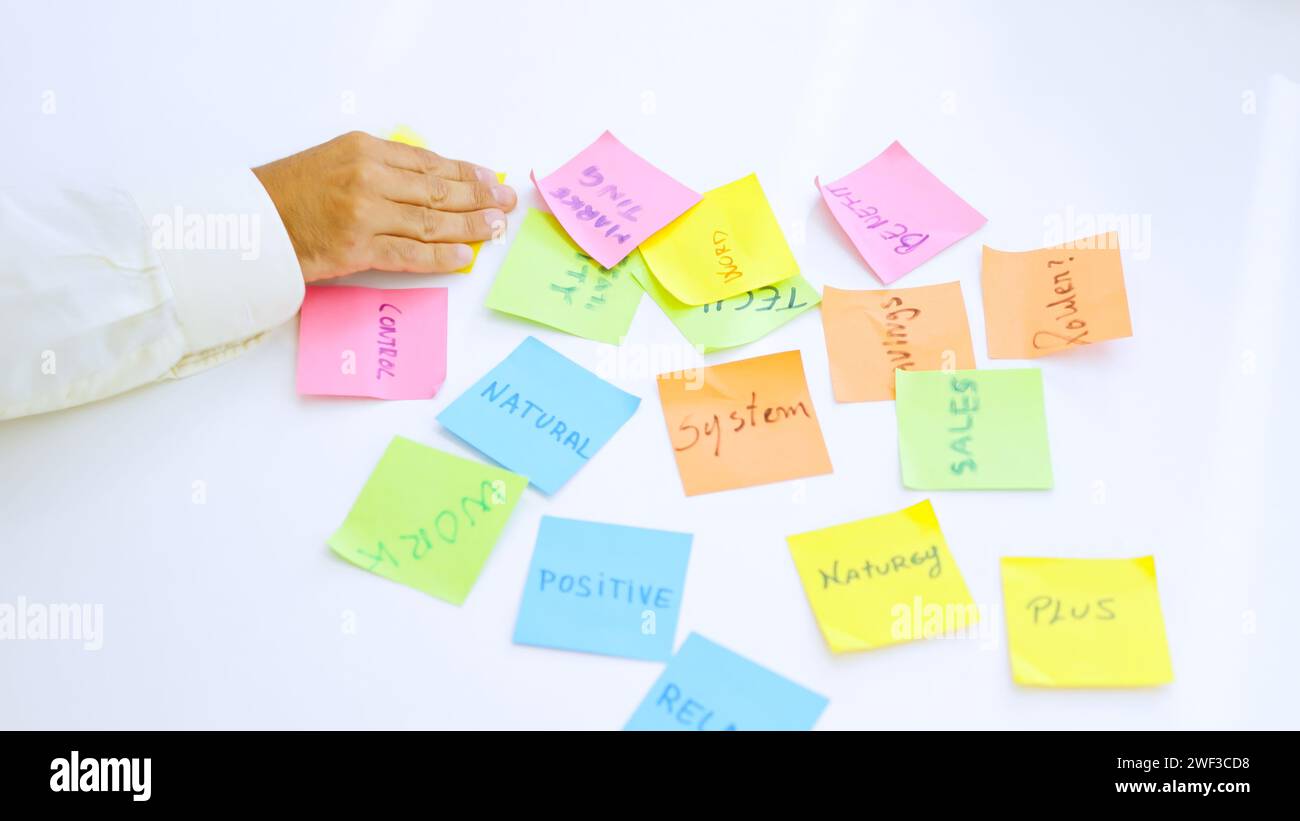 People using adhesive notes to write ideas on a table Stock Photo