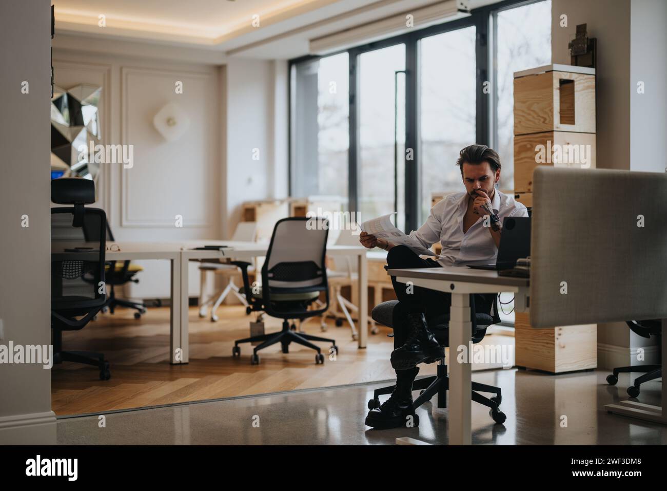 Focused young entrepreneur analyzing documents in a modern office Stock Photo